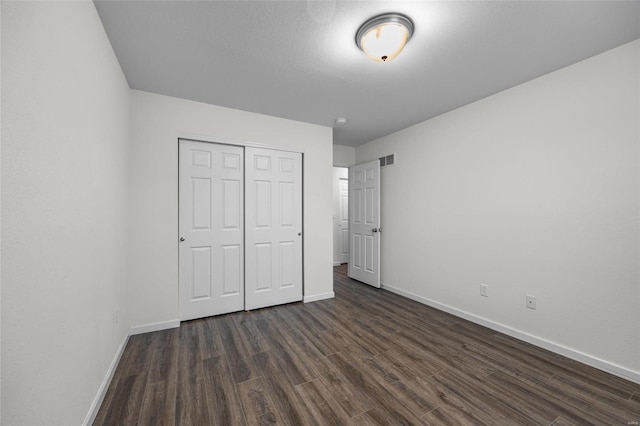 unfurnished bedroom with a closet and dark hardwood / wood-style floors