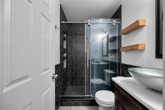 bathroom featuring vanity, toilet, an enclosed shower, and a textured ceiling