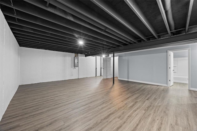 basement featuring hardwood / wood-style floors and electric panel