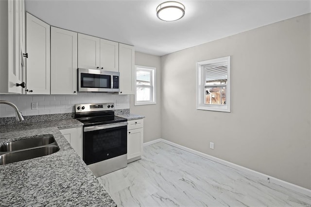 kitchen featuring white cabinetry, sink, dark stone counters, and appliances with stainless steel finishes