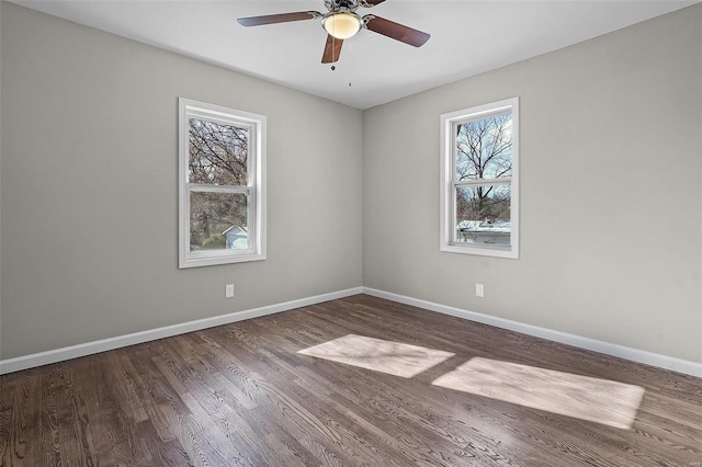 empty room with dark hardwood / wood-style floors, a wealth of natural light, and ceiling fan