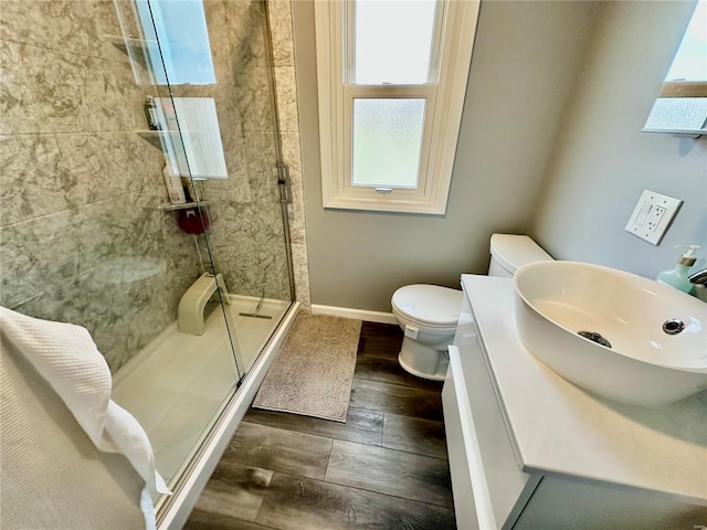 bathroom with wood-type flooring, toilet, a shower with shower door, and vanity