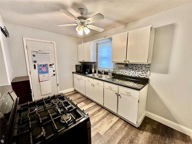 kitchen featuring sink, black gas range, and white cabinets