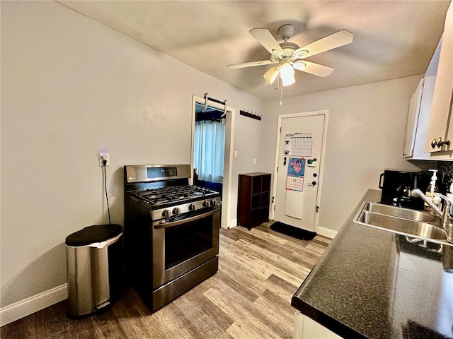 kitchen with stainless steel gas range, sink, light hardwood / wood-style flooring, ceiling fan, and white cabinets