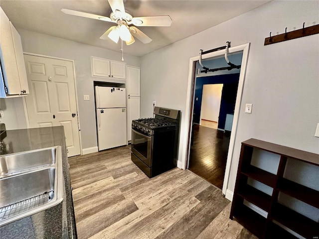 kitchen featuring stainless steel gas range, light hardwood / wood-style flooring, white refrigerator, ceiling fan, and white cabinets