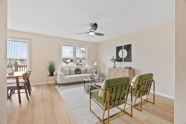 living room with ceiling fan, plenty of natural light, a textured ceiling, and light hardwood / wood-style floors