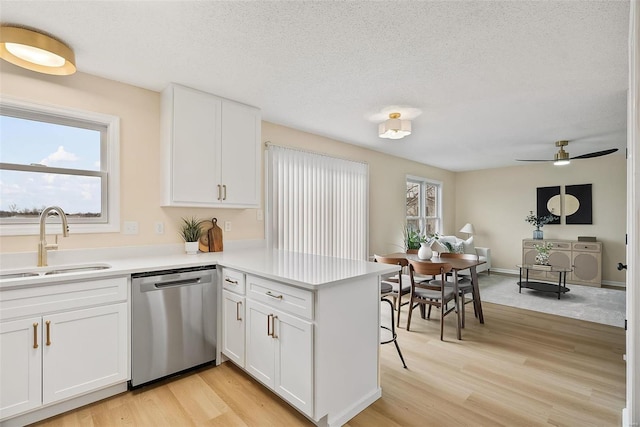 kitchen featuring white cabinetry, sink, stainless steel dishwasher, and kitchen peninsula