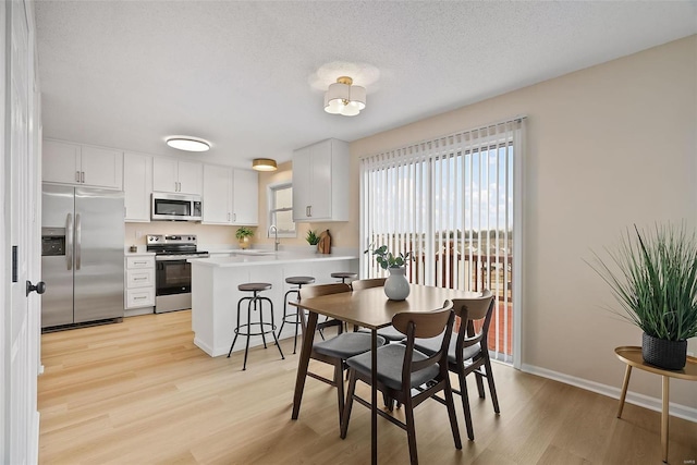 dining room with sink, light hardwood / wood-style floors, and a textured ceiling