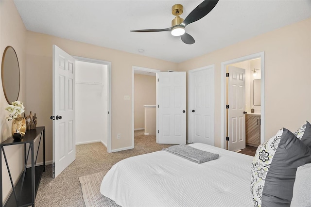 carpeted bedroom featuring a walk in closet, connected bathroom, ceiling fan, and a closet