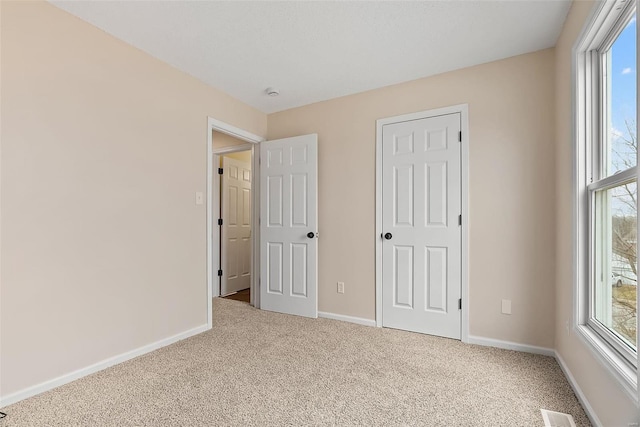 unfurnished bedroom featuring multiple windows and light colored carpet