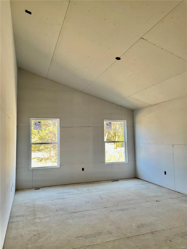 empty room with a wealth of natural light and vaulted ceiling