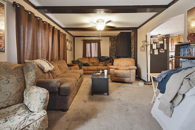 carpeted living room featuring beam ceiling, ceiling fan, and a textured ceiling