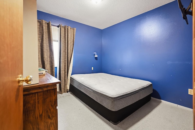 bedroom featuring light colored carpet and a textured ceiling