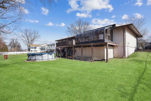 back of house with a swimming pool side deck, a sunroom, and a lawn