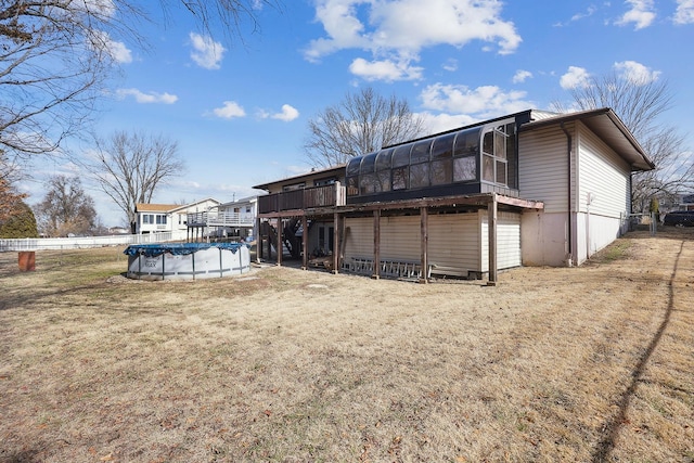 rear view of property featuring a pool side deck, a yard, and a sunroom