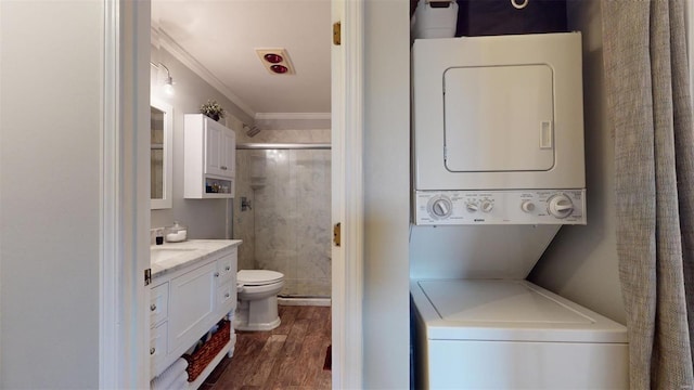 washroom with stacked washer and dryer, ornamental molding, and dark hardwood / wood-style flooring