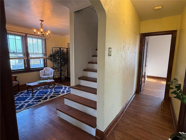 stairs with hardwood / wood-style floors and a chandelier