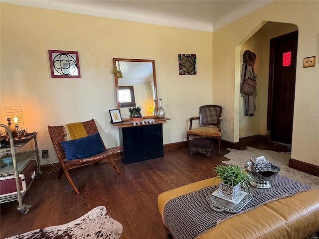 living room featuring arched walkways, baseboards, and wood finished floors