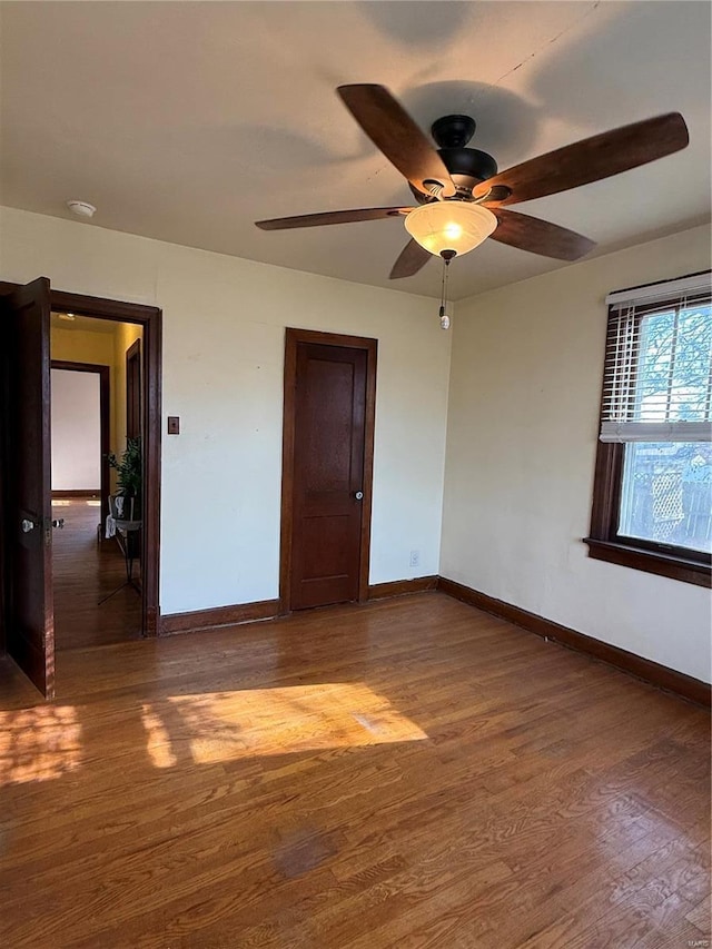 empty room featuring ceiling fan, baseboards, and wood finished floors