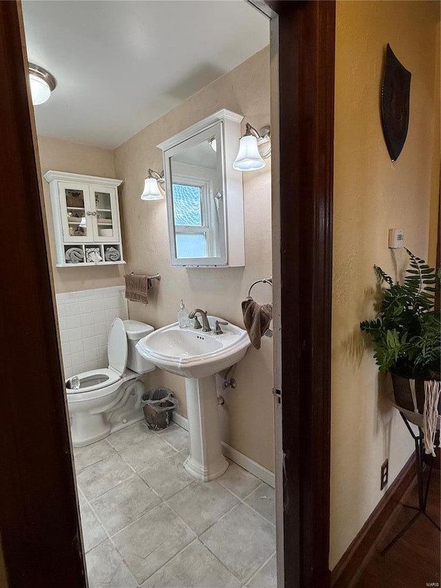 bathroom with tile patterned flooring, toilet, baseboards, and a sink