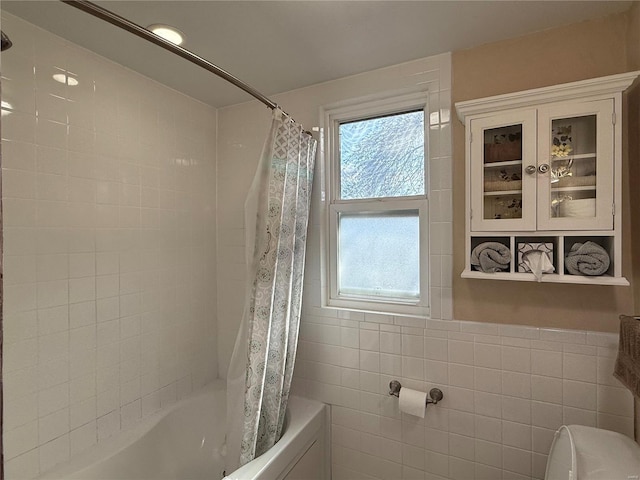 bathroom with tile walls, toilet, and shower / tub combo with curtain