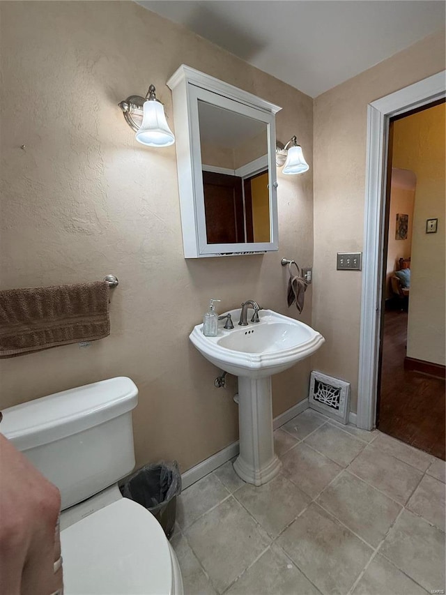 half bathroom with visible vents, baseboards, toilet, and tile patterned flooring