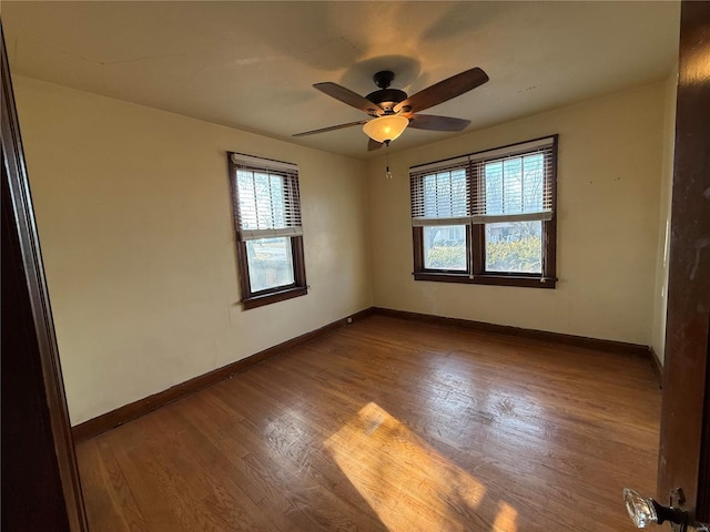 unfurnished room featuring baseboards, wood finished floors, and a ceiling fan