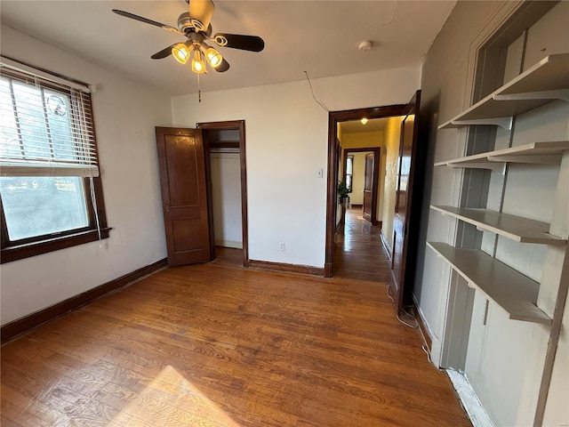 unfurnished bedroom featuring wood finished floors, baseboards, and a closet