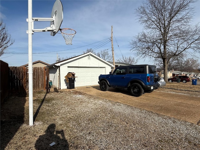 view of yard featuring an outdoor structure, fence, a garage, and driveway