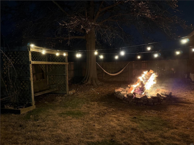 yard at night with a fire pit and fence