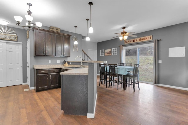 kitchen with hanging light fixtures, dark brown cabinets, sink, and dark wood-type flooring