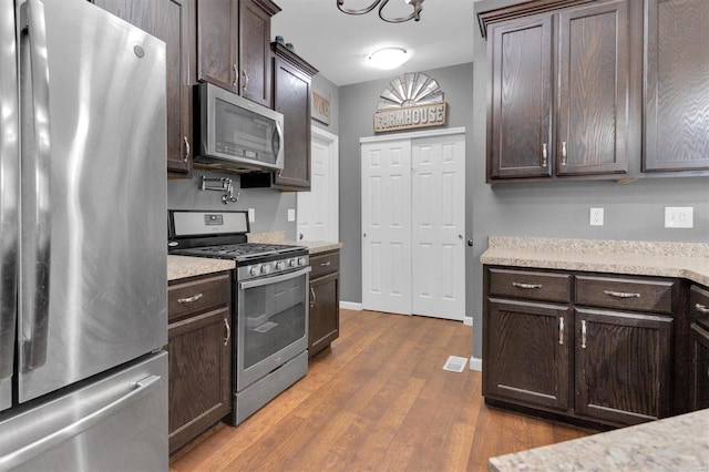 kitchen featuring appliances with stainless steel finishes, dark hardwood / wood-style flooring, and dark brown cabinets