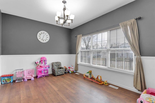 rec room with a notable chandelier and dark wood-type flooring