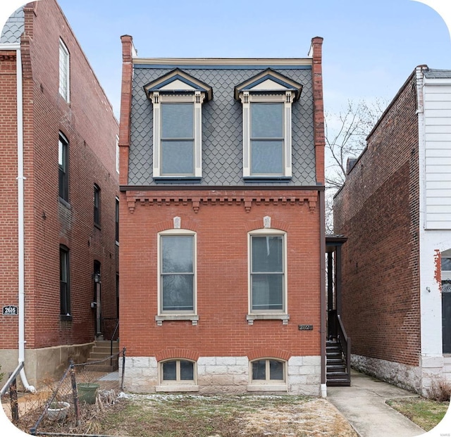 view of front of home featuring mansard roof, brick siding, and entry steps