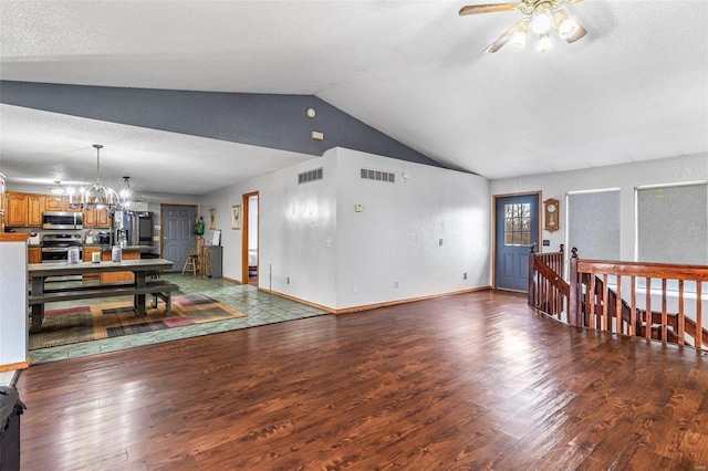 living room with lofted ceiling, ceiling fan with notable chandelier, a textured ceiling, and dark hardwood / wood-style flooring