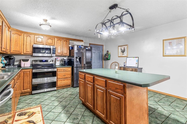 kitchen featuring appliances with stainless steel finishes, hanging light fixtures, dark tile patterned floors, a center island, and a textured ceiling