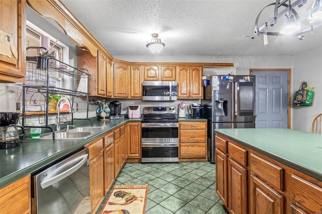 kitchen featuring sink, light tile patterned floors, a textured ceiling, and appliances with stainless steel finishes