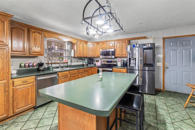 kitchen with sink, stainless steel appliances, a center island, and a textured ceiling