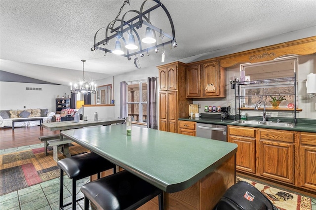 kitchen with a kitchen bar, sink, a center island, stainless steel dishwasher, and pendant lighting