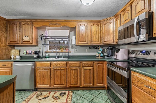 kitchen featuring appliances with stainless steel finishes, sink, light tile patterned floors, and a textured ceiling