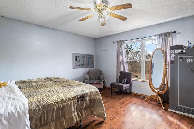 bedroom featuring ceiling fan, dark wood-type flooring, and a textured ceiling