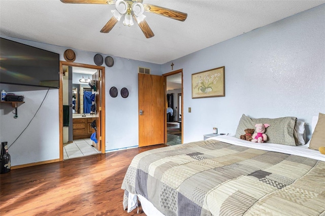 bedroom featuring ceiling fan, connected bathroom, a textured ceiling, and light wood-type flooring