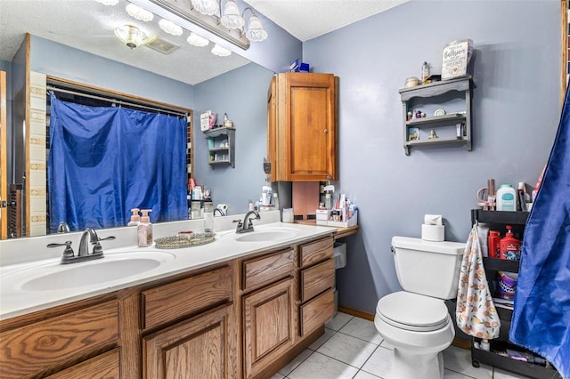 bathroom featuring tile patterned flooring, vanity, a textured ceiling, and toilet