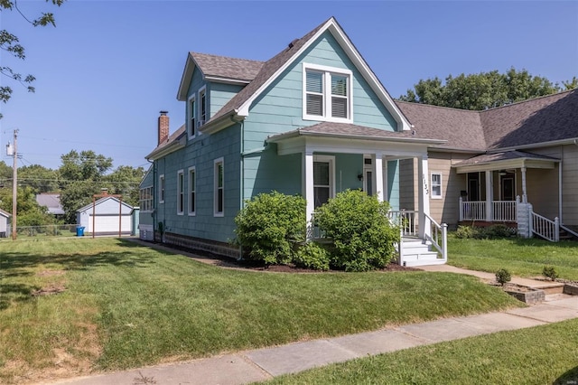 view of front facade with a garage, an outdoor structure, covered porch, and a front lawn