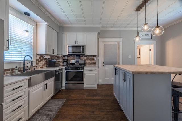 kitchen with hanging light fixtures, stainless steel appliances, a kitchen breakfast bar, and white cabinets