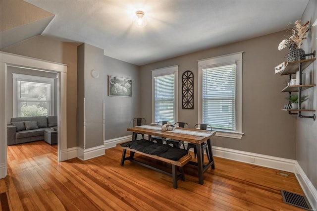 dining room featuring a wealth of natural light, light hardwood / wood-style floors, and vaulted ceiling