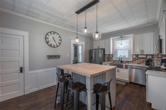 kitchen with appliances with stainless steel finishes, sink, a kitchen island, and white cabinets