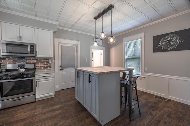 kitchen featuring pendant lighting, white cabinetry, butcher block counters, a center island, and stainless steel appliances