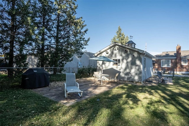 back of property with a patio, a yard, and an outbuilding