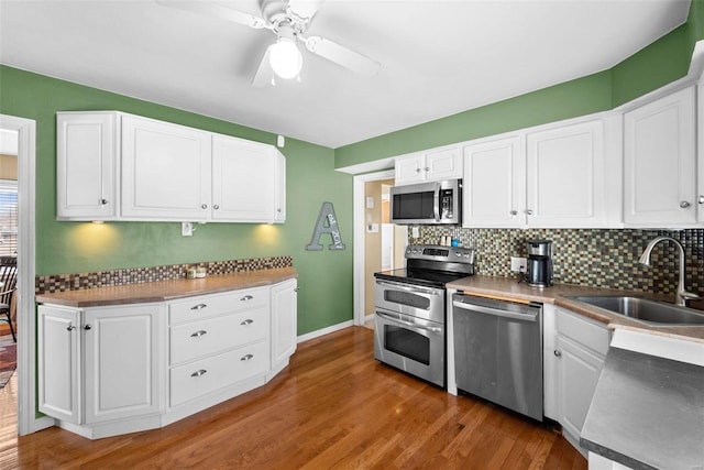 kitchen featuring sink, appliances with stainless steel finishes, white cabinetry, dark hardwood / wood-style floors, and tasteful backsplash